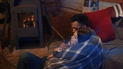 Couple sitting by the burning fireplace in a cozy house . High quality photo