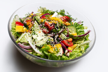 Close-up of transparent bowl with green salad on white background.