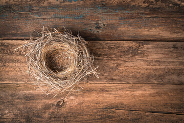 Nest made of dry grass on a natural wooden background. Top view, horizontal, with space to copy.