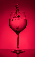 Splash of water in a glass on a red background. Unusual sculptures