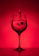 Splash of water in a glass on a red background. Unusual sculptures