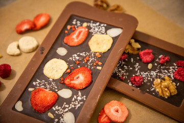 Handmade chocolate with fresh and dried fruits on light paper background in rustic style
