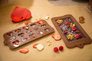 Handmade chocolate with fresh and dried fruits on light paper background in rustic style