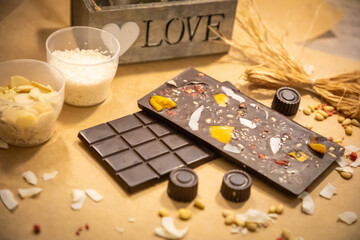 Handmade chocolate with fresh and dried fruits on light paper background in rustic style