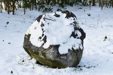 Decorative stone covered with snow in the park. 