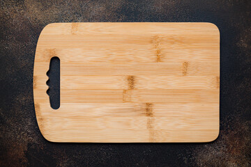 New rectangular bamboo wooden cutting board on stone background. Top view. Mock up for food project.