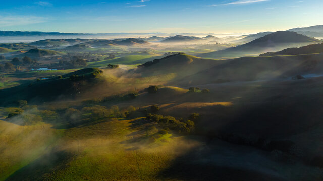 Aerial view countryside farm hills and valleys at sunrise with fog, California