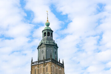 Fototapeta na wymiar Top of the Walburgiskerk tower against a blue sky with wave pattern clouds