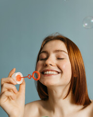 Model with naked shoulders smiling and blowing bubbles