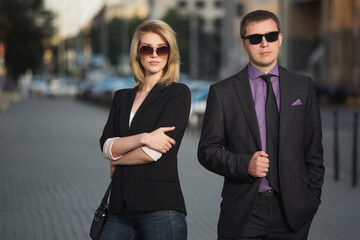 Young fashion business couple walking on city street