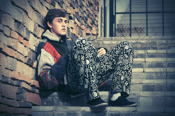 Sad young hipster man sitting on the steps
