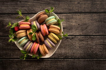 Colorful macaroni cakes. Small French cakes. Sweet and colorful French macarons are plates in the shape of a heart. Top view. Copy Space