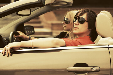 Happy young couple driving convertible car