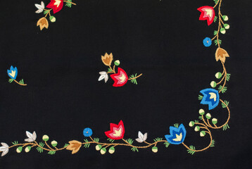 The horizontal photo of the traditional Norwegian vest-coast embroidery ornament, called Frafjord,  on the black woolen fabric