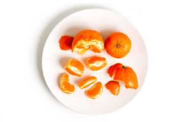 Peeling Tangerines or Clementines in White Plate, isolated on white background