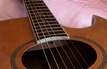 Closeup of the sound hole of an electric-acoustic guitar, with thick strings and an enamel fret...