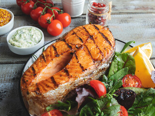 grill fish steak salmon with fresh salad and tomatoes, white sauce, dijon mustard, top view