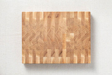 Oak spliced ​​wooden cutting board on burlap.  The cross-section of the oak plank has a mosaic texture.