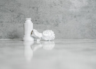 A plaster bust of a woman fell from a pedestal and broke off. Plaster head on a gray background. A space for insertion. Concept it hurts to fall off a pedestal. Copy space