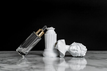 Transparent cosmetic serum in a pipette bottle on a gray and black background. Next to it is a white plaster bust of a woman. The concept of care and destruction