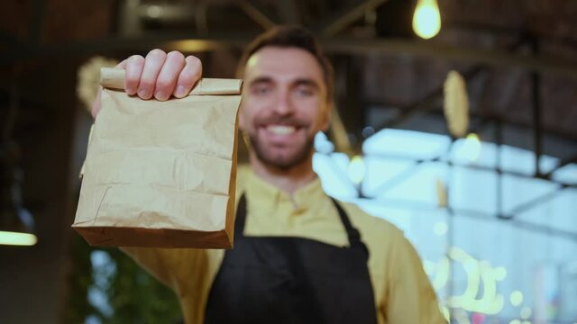 A paper food package with order in hands of barista waiter