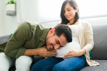 Excited latin man hearing his baby moving in the belly of his wife