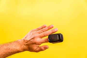 An adult is monitored for oxygen saturation and pulse with a homemade oximeter, isolated on a yellow background.