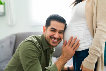Latin man hearing his baby moving in the belly of his wife