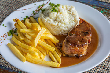 Filet mignon wrapped in bacon with rice and french fries. Children's plate