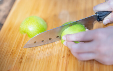 Female hand holding knife and  preparing cut off the fresh green apple for made the juice, The fresh fruit  food concept.