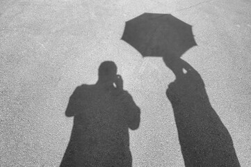 Shadows on the pavement. Male shadow and the shadow of a woman with an opened umbrella.