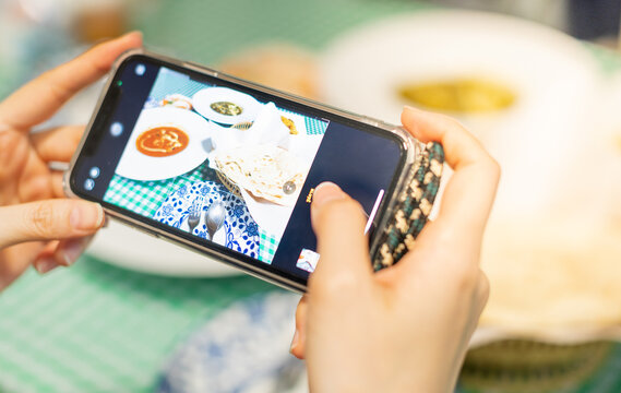 Female hand holding smartphone and taking picture the Egyptian food on the table, for update status or moment in social media
