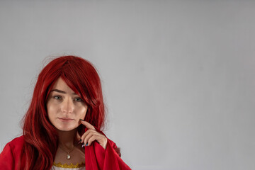 Full length young female attractive model in a studio with a white background, the model is wearing a red medieval costume with red auburn hair