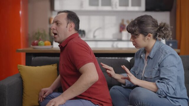 Woman massaging her partner's shoulder and back, suffering from back pain.The woman rubs and massages the sore spots with her hand.