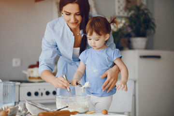 Family in a kitchen. Beautiful mother with little daughter. Woman in a blue shirt