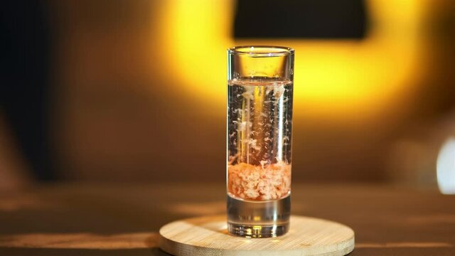 The bartender pushes forward a glass with a ready drink: baileys in sambuca. Preparation of exclusive drinks in the nightclub.