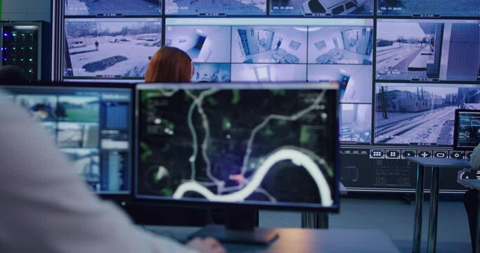 Employees watching camera footage in security center