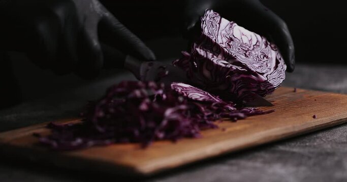 4K Women Hand cutting fresh red cabbage on Cutting Board. Female hand slices raw red cabbage into little slide with knife on cutting Board. healthy food concept