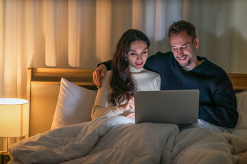 couple watching movie with laptop computer together on bed