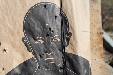 Close up on man shaped range target on the shooting range after the training with bullet holes -...