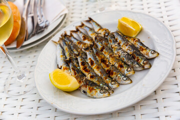 Close up of Andalusian fried sardines on white plate on white tablecloth