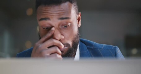 Young african businessman working overtime on laptop at office late night. - Powered by Adobe