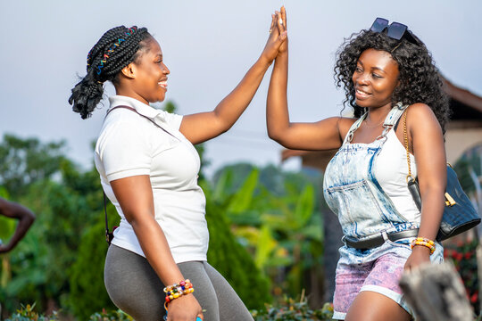 candid image of beautiful african ladies with joint hands- excited black girls having fun- outdoor concept