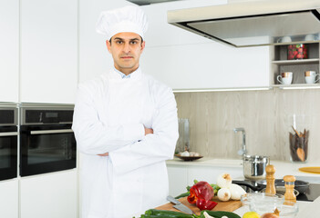 Portrait of man cook who is standing on his work place in the kitchen at the cafe.