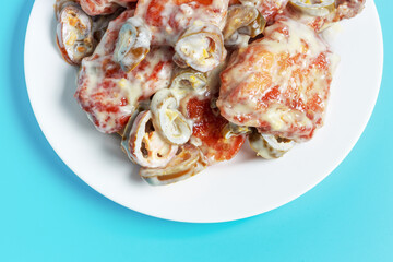 Cooked korean chicken on white plate on a blue background, top view.