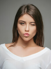 People emotions. Happy teen woman winking and kiss. Cute girl face portrait.
