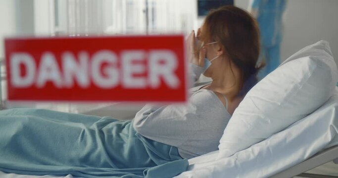 Infected with covid-19 patient with dry cough symptom lying in ward with danger sign on glass door