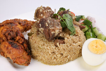 Beef Biryani Tehari with boiled egg coriander leaf garnish chicken curry pot roasted leg tomato cucumber onion chili coriander salad on white plate set over white background