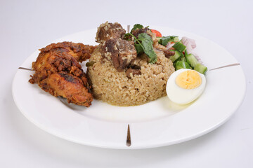 Beef Biryani Tehari with boiled egg coriander leaf garnish chicken curry pot roasted leg tomato cucumber onion chili coriander salad on white plate set over white background