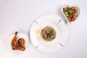 Beef Biryani  with boiled egg coriander leaf garnish on white plate chicken curry pot roasted leg triangle dish tomato cucumber onion coriander salad hart shape dish set over white background